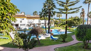 A resort with a swimming pool, lounge chairs, and palm trees.