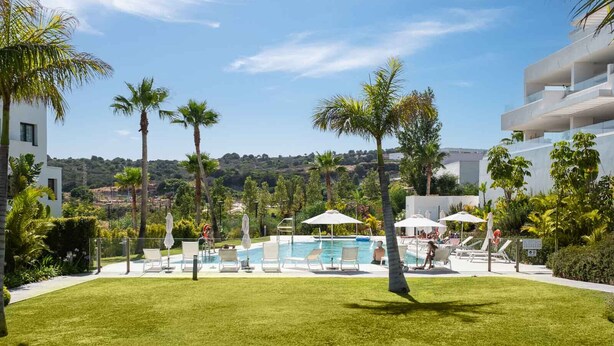 A pool area with lounge chairs and umbrellas, surrounded by palm trees and a view of a hilly landscape. - Olas Sunset by Alfresco Stays (Estepona)