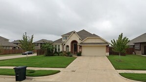 A suburban house with a front driveway, a garage, and a well-maintained lawn. - Beautiful House in Mansfield (Mansfield)