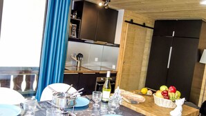 A modern kitchen with dark cabinets, a wooden countertop, and a dining area with blue plates and silverware.