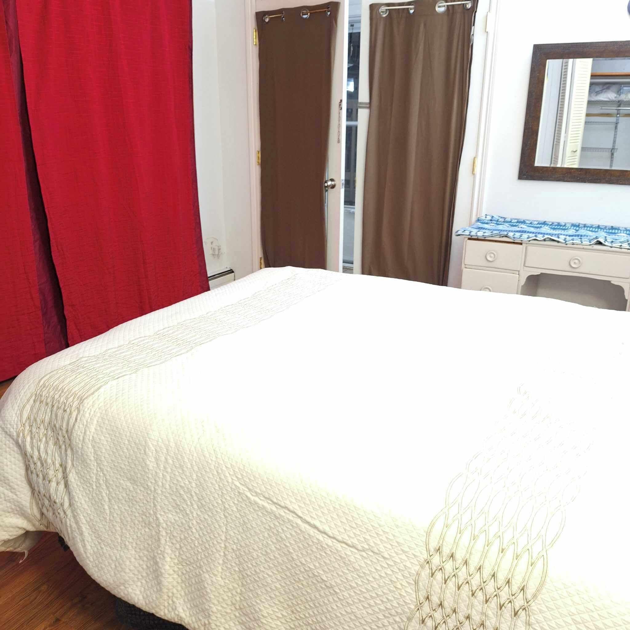 Une chambre à coucher avec un lit, une commode et un miroir.