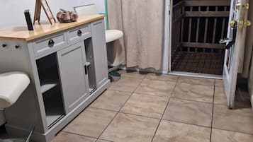 A small, compact room with a kitchenette, a toilet, and a door leading to a balcony.