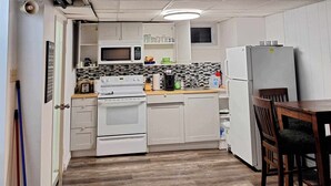 A compact kitchen with white cabinets, a microwave, a stove, and a refrigerator.
