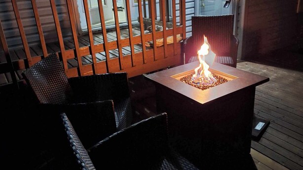 An outdoor seating area with a table and chairs, a fire feature, and a wooden fence.