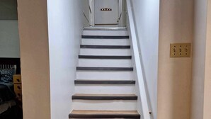 A staircase with wooden steps and white walls, leading to a landing with a light switch.