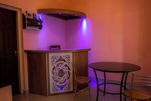 A bar area with a wooden counter, a decorative panel, and two chairs.