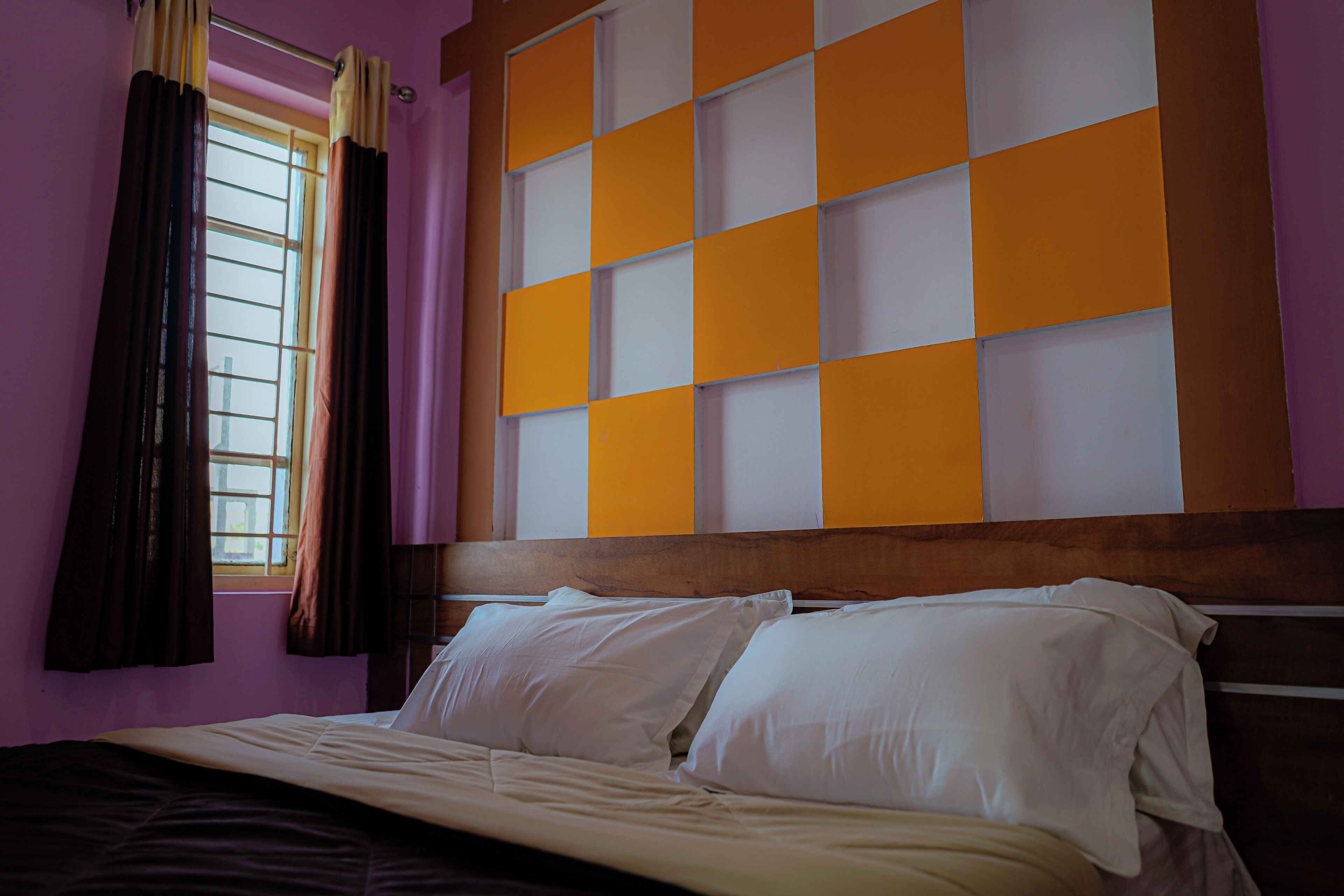 A room with a bed, curtains, and a wall with a checkered pattern.