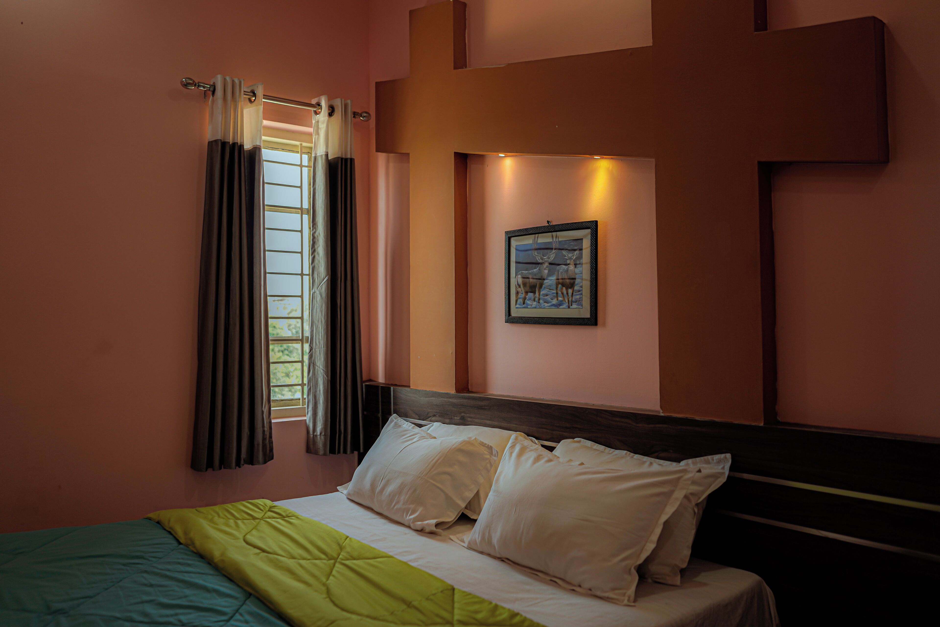 A bedroom with a bed, curtains, a framed picture on the wall, and a window with curtains.