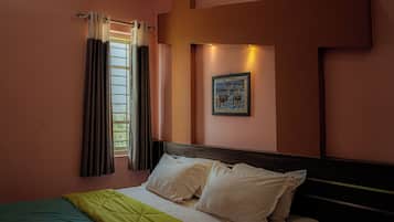 A bedroom with a bed, curtains, a framed picture on the wall, and a window with curtains.