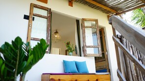 A wooden bench with a cushion, a rustic wooden door frame, and a hanging light fixture. - Stop And Go Lang Chai Bau Trang (Bac Binh)