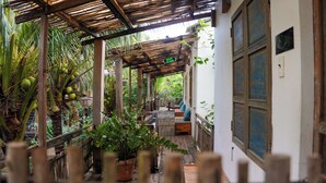 Un espace extérieur abrité, doté d’un banc en bois, de plantes en pot et d’un panneau indiquant une sortie.