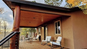 Une terrasse en bois avec des sièges extérieurs et un escalier menant à une zone abritée.