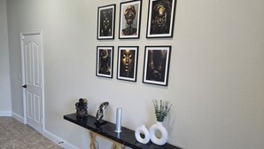 A hallway with a black marble console table, framed artwork on the wall, and a white door.