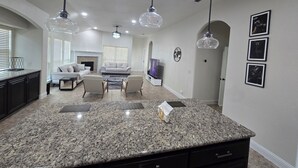 A spacious living area with a large granite island, dark cabinetry, and a fireplace.