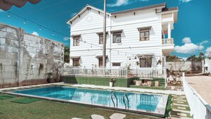 A two-story white house with a swimming pool, a white picket fence, and string lights. - Thu Hien Hotel Pleiku - by BAY LUXURY (Gao)