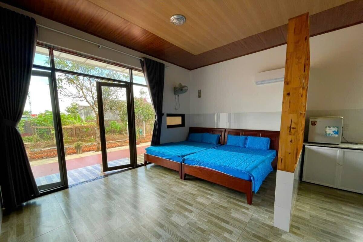 Una habitación con cama, kitchenette y un amplio ventanal corredera que da a un espacio exterior.