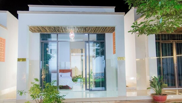A modern building with a glass entrance, a wooden ceiling, and a bed visible inside. - Thu Hien Hotel Pleiku - by BAY LUXURY (Gao)