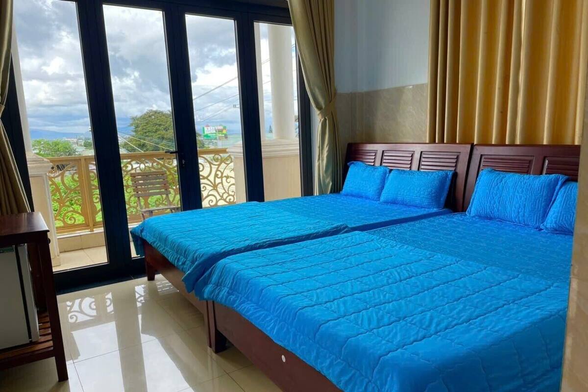 Una habitación de hotel con una cama grande, una mesita pequeña y un balcón con vistas.