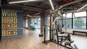 Ein Fitnessstudio mit Trainingsgeräten, einer motivierenden Wand und großen Fenstern.