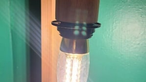 A hanging light fixture with a wooden base and a clear glass shade, mounted on a wooden beam. - So Art Hostel (Sanyi)