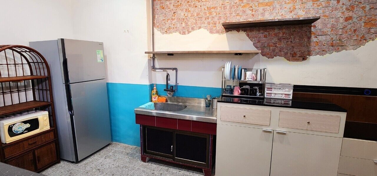 Cocina compacta con refrigerador, lavamanos y armarios.