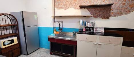 Cocina compacta con refrigerador, lavamanos y armarios.