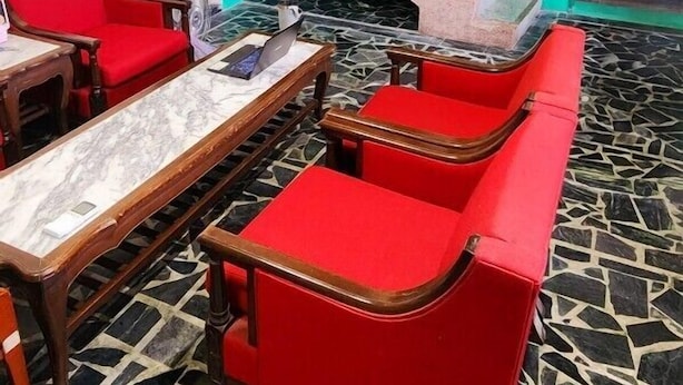 A room with a red sofa set, a marble-topped table, and a staircase with a wooden door. - So Art Hostel (Sanyi)