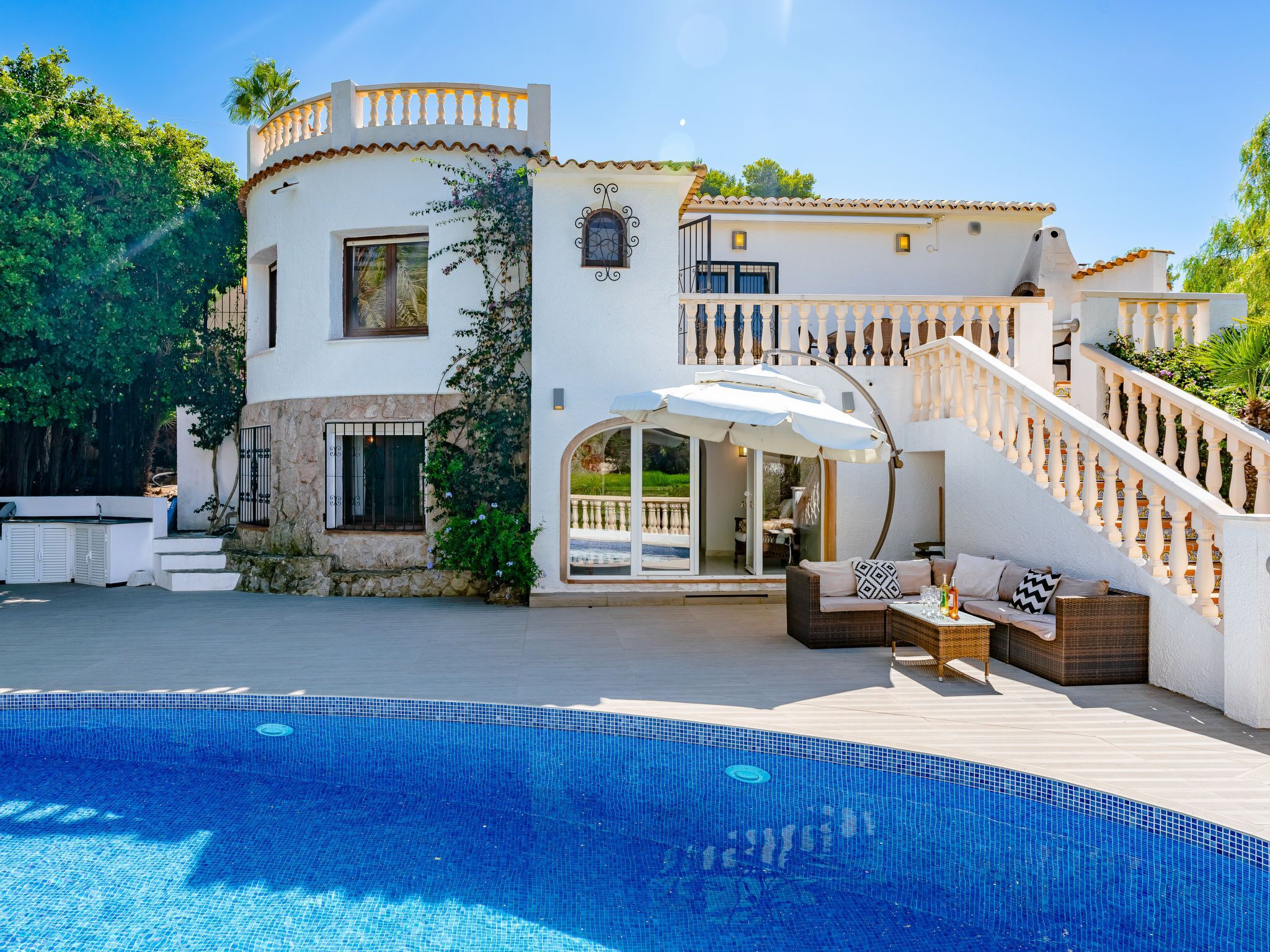 Une villa moderne dotée d’une piscine, d’un espace salon extérieur et d’un escalier menant à un balcon.