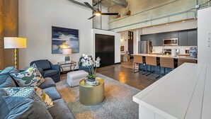 A modern living room with a sofa, a coffee table with flowers, a lamp, and a painting on the wall. - Hebrews 13:2- Wonderful 2 bedroom condo downtown Waco, Baylor, Silos (Waco)