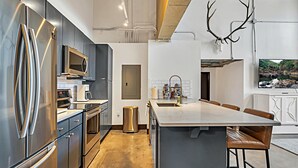 A modern kitchen with stainless steel appliances, a large island, and a mounted deer skull. - Hebrews 13:2- Wonderful 2 bedroom condo downtown Waco, Baylor, Silos (Waco)