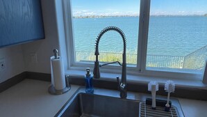 Une cuisine équipée d’un évier, d’une fenêtre donnant sur un plan d’eau et offrant une vue sur un quai.