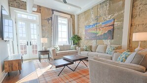 Een ruime woonkamer met een grote zithoek, een bijzettafeltje en een vloerkleed met dessin.