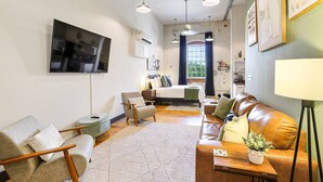 A modern living room with a sofa, armchairs, a coffee table, and a TV mounted on the wall.