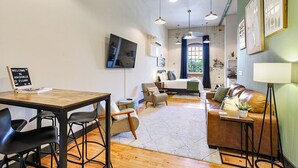 A modern living room with a sofa, a coffee table, and a dining area with chairs and a table.