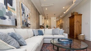 A living room with a sectional sofa, a glass coffee table, and a patterned rug. - Historic Elegance on Gay Street (Knoxville)
