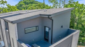 A modern two-story building with a flat roof, a balcony, and a door leading to an enclosed porch.