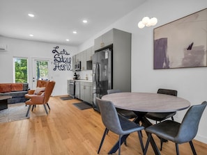 A modern kitchen with a dining area, a sofa, and a wall with a motivational quote.