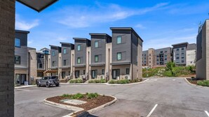 Un immeuble d’appartements moderne doté d’une cour intérieure, d’une allée pavée et d’un véhicule stationné sur le parking.