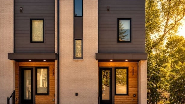 Un immeuble résidentiel moderne à deux étages, doté d’un toit plat, de grandes fenêtres et d’une pelouse bien entretenue.