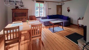 A wooden dining table with chairs, a sofa, and a small table with a floral tablecloth. - 3 bedroom lovely home in Likenäs (Likenäs)