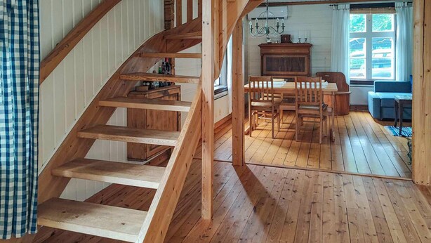 A wooden staircase leading to a dining area with a table and chairs, a blue sofa, and a window with a view of the outside. - 3 bedroom lovely home in Likenäs (Likenäs)