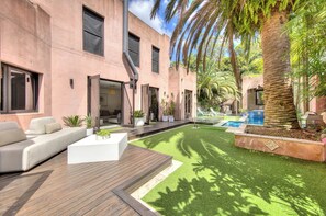 A modern outdoor living area with a wooden deck, a pool, and a well-maintained lawn.