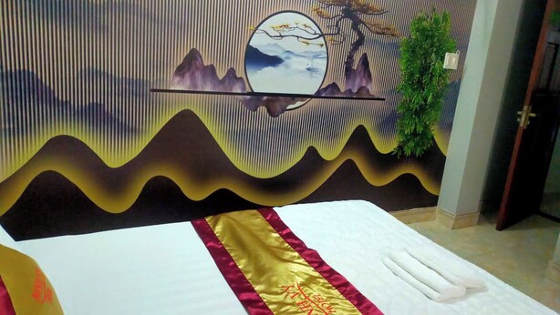 Una habitación de hotel con una cama, un detalle decorativo en la pared y una planta.