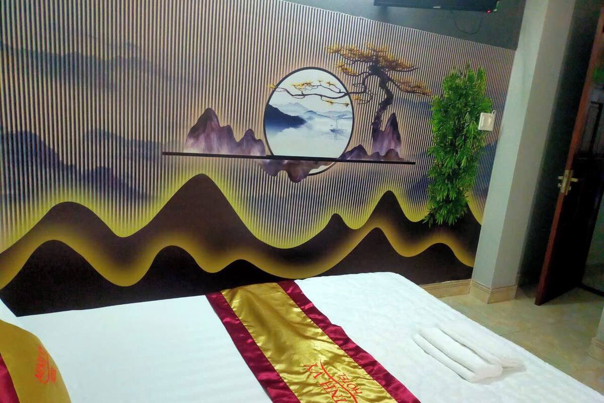 Une chambre d’hôtel avec un lit, un mur décoratif et une plante.