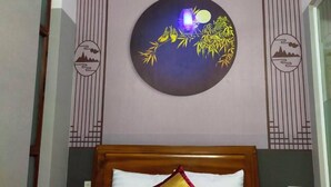 Una habitación de hotel con cama, luz nocturna y decoración en la pared.