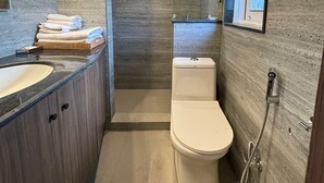 A modern bathroom with a wooden ceiling, a large mirror, a toilet, a sink, and a shower. - The Magnolia Srinagar (Srinagar)