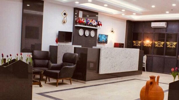 A modern reception area with a marble floor, black and white decor, and a large vase on a table. - Seta Park Hotel (Inegöl)