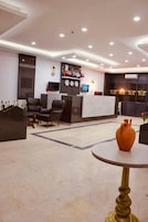 A modern reception area with a marble floor, black and white decor, and a large vase on a table.