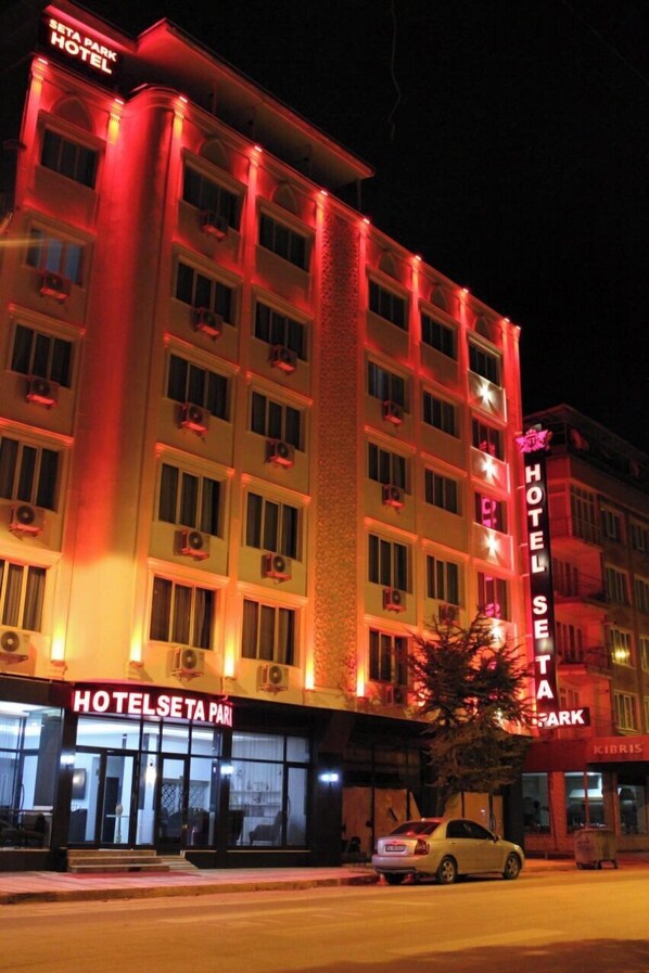 A multi-story hotel with illuminated signage, a car parked in front, and a visible entrance. - Seta Park Hotel (Inegöl)