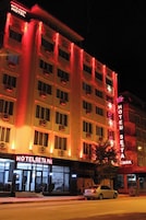 A multi-story hotel with illuminated signage, a car parked in front, and a visible entrance.